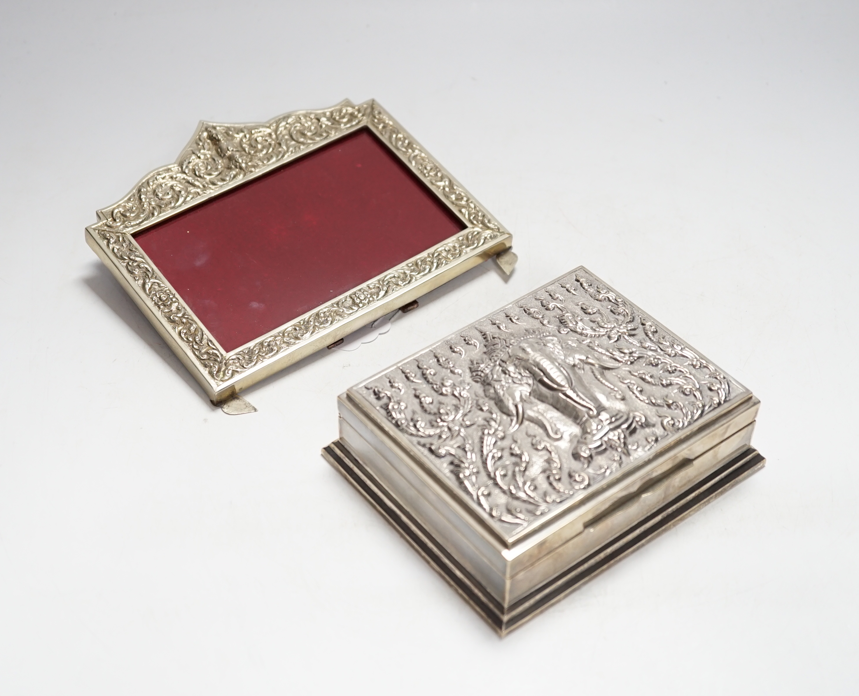 A Thai white metal cigarette box, stamped sterling, 14cm, and a similar sterling overlaid photograph frame, width 16cm